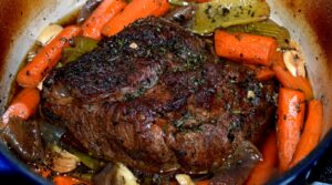 Ultra close up macro food photography of tender slow cooked beef chuck roast with carrots and rich pan gravy