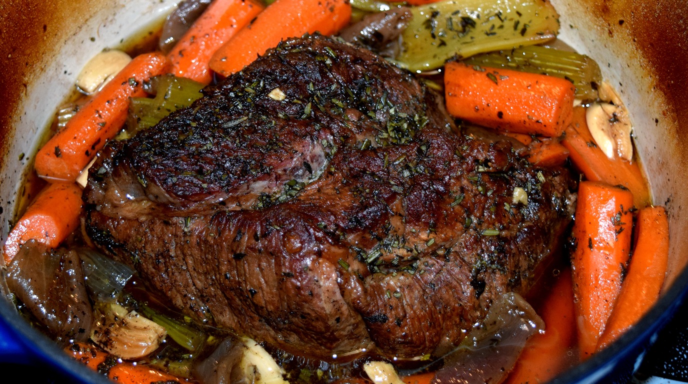 Ultra close up macro food photography of tender slow cooked beef chuck roast with carrots and rich pan gravy